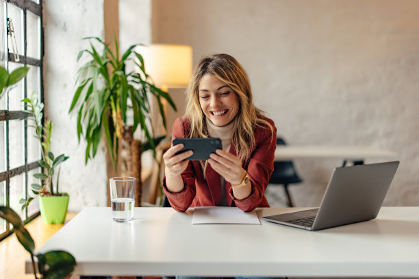 开朗的女上班族，用手机聊天，笑容可掬。图片下载