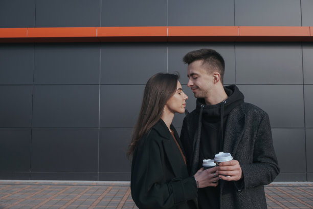 年轻的爱夫妻在黑色的工业背景下喝咖啡图片下载