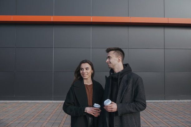 年轻的爱夫妻在黑色的工业背景下喝咖啡图片下载