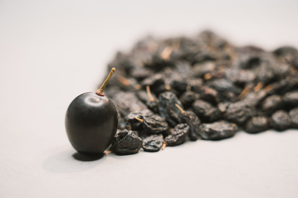 右图是一颗蓝色葡萄和一堆葡萄干的特写。上面有葡萄干的葡萄。图片下载