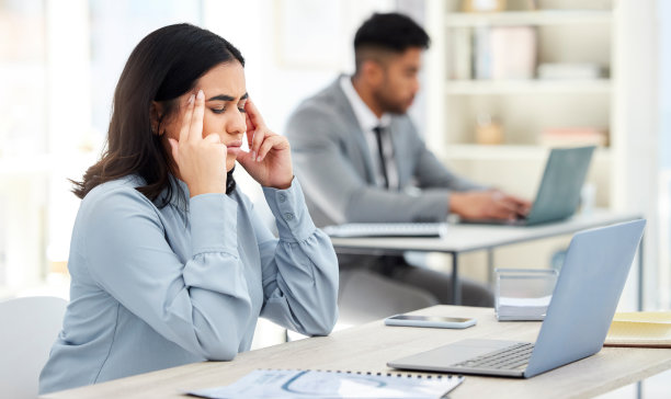 这张照片拍摄的是一位年轻的女商人，在办公室用笔记本电脑工作时，她看起来压力很大图片下载