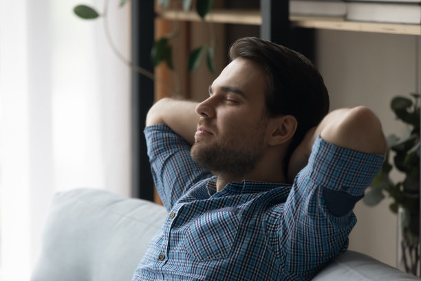 男人放松在沙发上做白日梦，享受周末在现代家庭图片下载