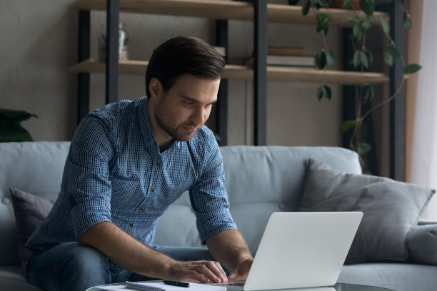 年轻的帅哥在家里用笔记本电脑工作图片下载