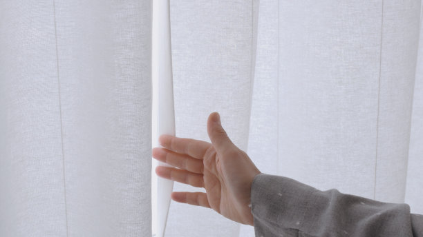 一个女人的手拉开了窗帘，窗外一片雪白的亮光充满了整个房间。早晨的阳光穿过那女人拉着的窗帘图片下载