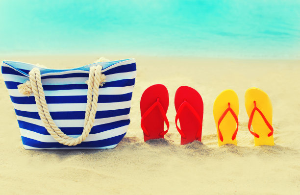 暑假概念-包和人字拖在海滩上蓝色的大海背景图片下载