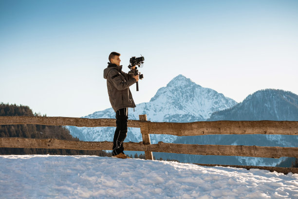 摄像师拍摄的镜头在雪和山的背景。图片下载
