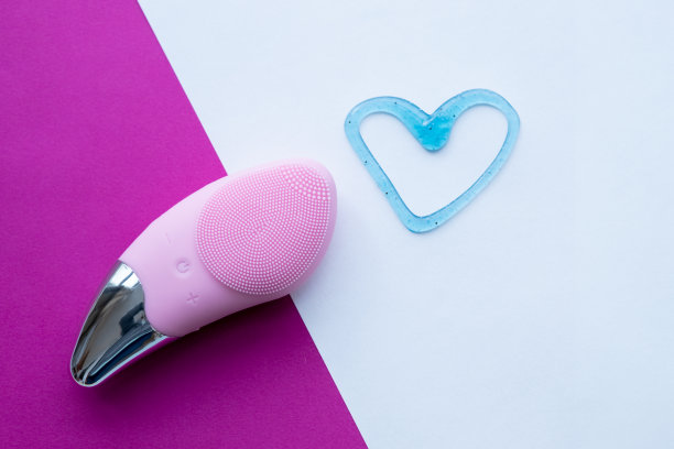 粉色硅胶洁面刷。皮肤护理用刷子。整容手术。第一步，皮肤清洁。剥皮，轻轻按摩面部。面部按摩器，俯视图。副本的空间。图片下载