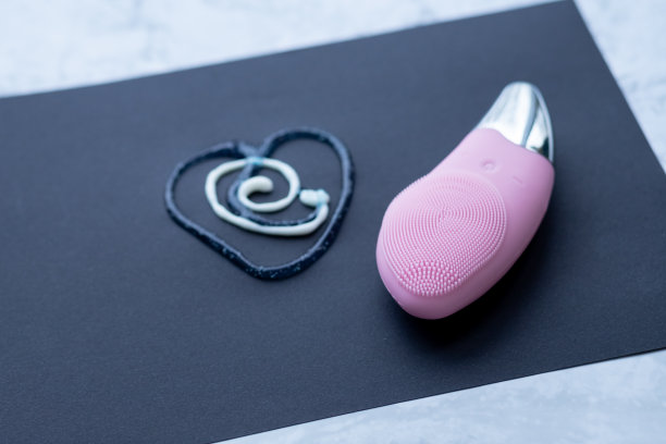 粉色硅胶洁面刷。皮肤护理用刷子。整容手术。第一步，皮肤清洁。剥皮，轻轻按摩面部。面部按摩器，俯视图。副本的空间。图片下载