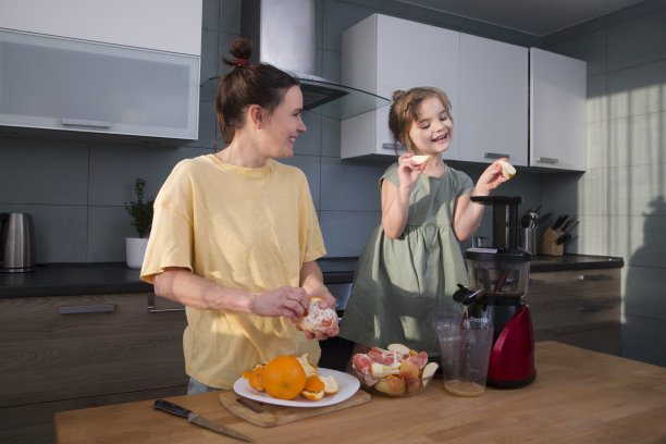 幸福的家庭母亲和孩子女儿一起制作果汁榨汁机。健康的饮食习惯。维生素图片下载