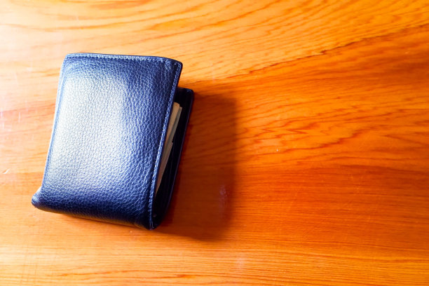 俯视图的新黑色真皮钱包与纸币和信用卡内部隔离在橙色木制背景。图片下载