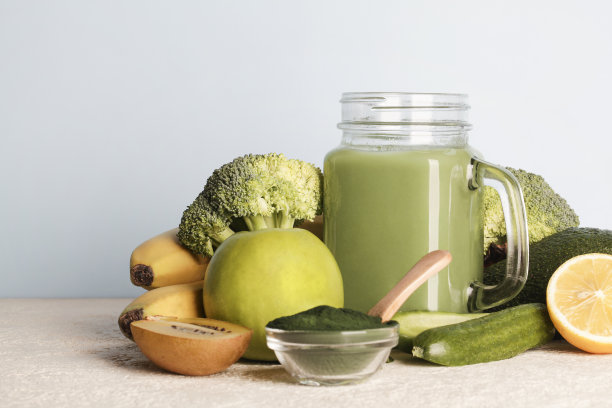 玻璃瓶绿色冰沙，螺旋藻粉，蓝色背景的蔬菜和水果。健康、生、纯素的饮食理念。本空间图片下载