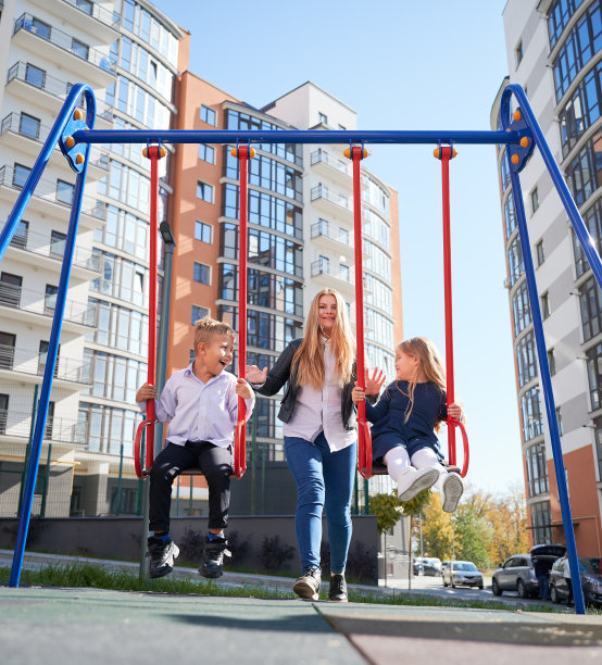 母亲让孩子们在操场上荡秋千。图片下载