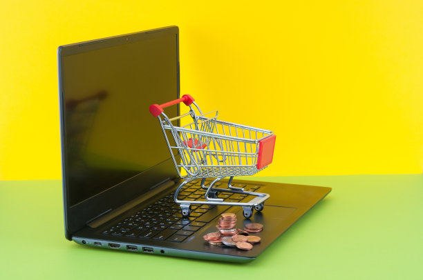 购物车和笔记本电脑上的硬币在绿色和黄色的背景图片下载