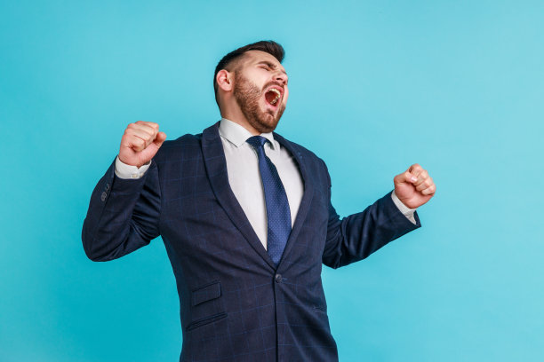 年轻有魅力的络腮胡商人身穿深色正装，打哈欠并举起双手，感到加班疲劳图片下载