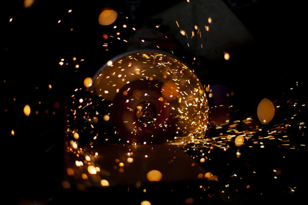 锯切钢。金属上的锯子。钢材型材的切割。火花在黑暗。主创造设计。图片下载