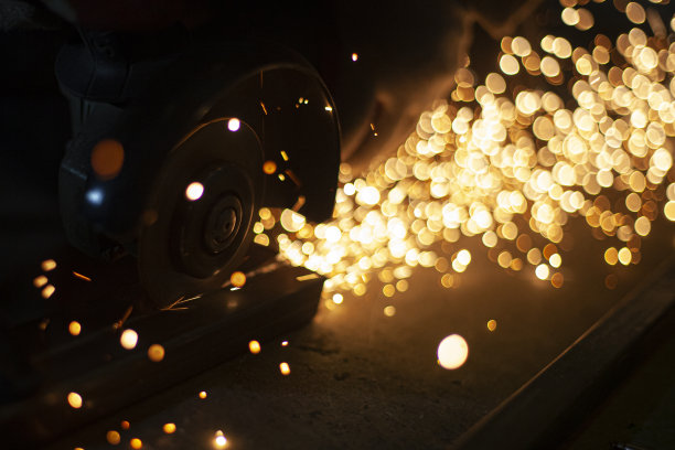 火花在黑暗。金属研磨。橙色的光会朝不同的方向飞。在金属车间工作。钢材加工用磨床。图片下载