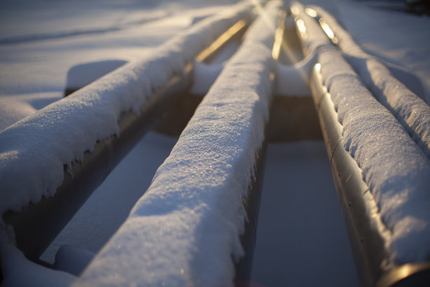 雪地里的暖气管。街道上的城市交通。热水供应管道与锅炉房。图片下载