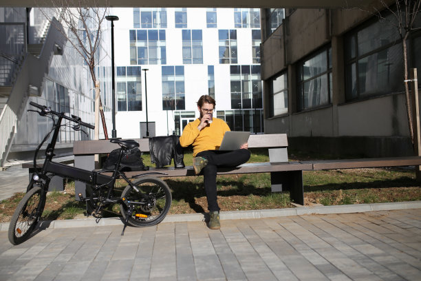 骑着电动自行车的上班族用可重复使用的咖啡杯喝咖啡。库存图片图片下载