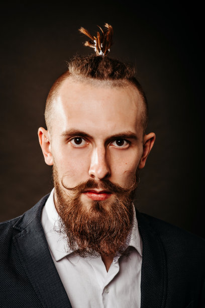 一个留着胡子的野蛮嬉皮士青年的肖像，在黑暗的背景下在工作室里留着长胡子图片下载