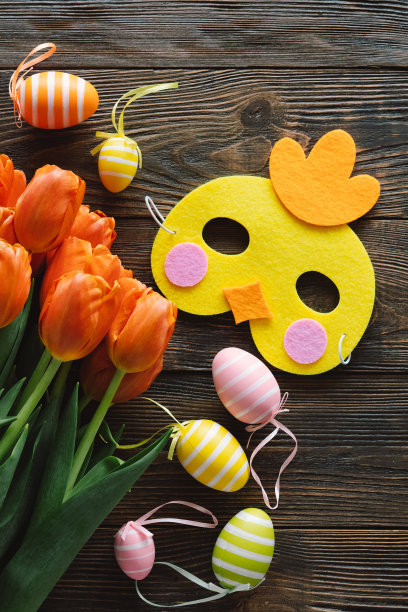 春天的郁金香和五彩缤纷的复活节彩蛋在木制的背景上。图片下载