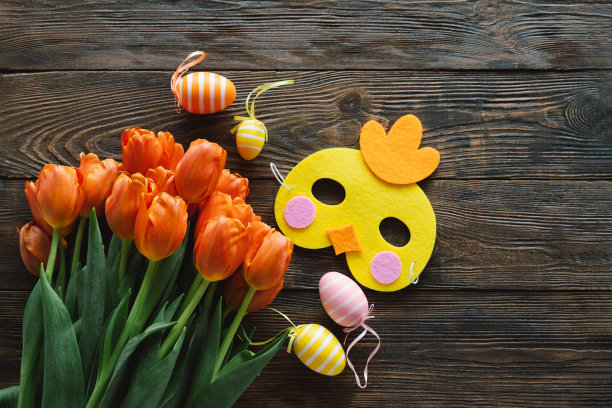 春天的郁金香和五彩缤纷的复活节彩蛋在木制的背景上。图片下载