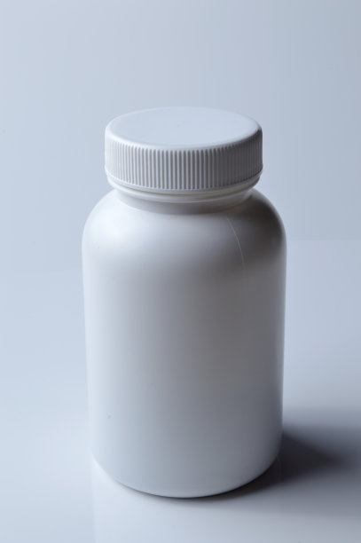 白色塑料药瓶和两个白色药丸。光背景。图片下载