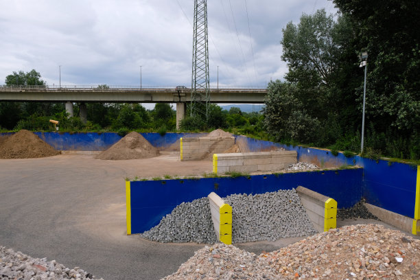 德国工业园区。一堆堆的鹅卵石和碎石被明亮的蓝色和黄色隔板隔开。图片下载