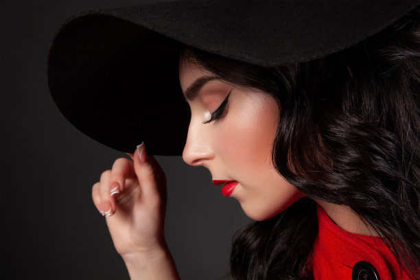 她是一个身材苗条的黑发女人，留着长长的卷发，化着漂亮的妆，穿着一件红色的外套。图片下载