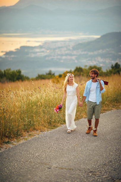年轻的夫妇，波西米亚风格的新婚夫妇，新娘和新郎带着吉他走在自然的道路上。自然、波西米亚、生活理念。图片下载