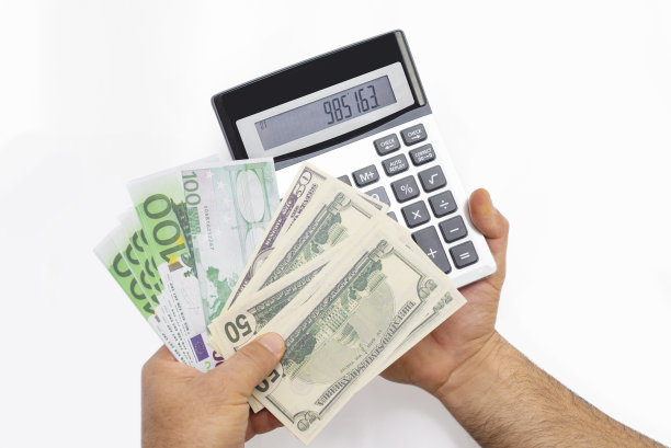 手里拿着计算器和500美元和欧元。图片下载