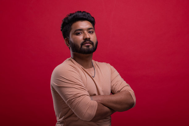自信，年轻的印度男人的肖像与胡子在红色的背景。图片下载