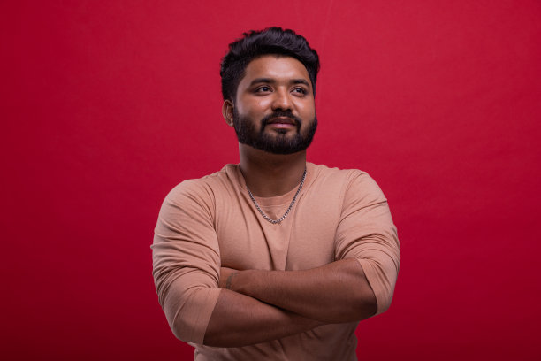 微笑着，年轻的印度男人的肖像，红色的背景是胡子。图片下载