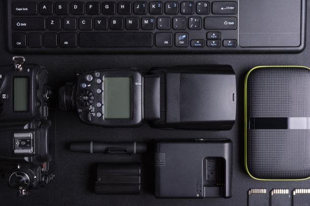 摄影师的工作空间配有数码相机、闪光灯、记忆卡、键盘和便携式硬盘图片下载