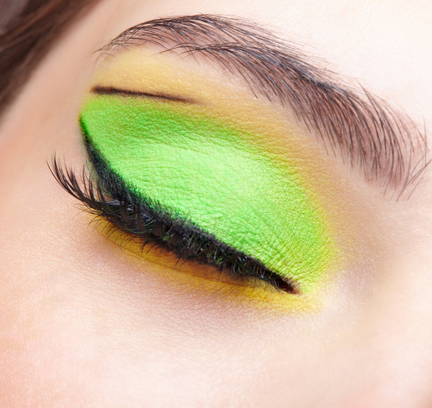 人类女性闭眼的特写微距镜头。有绿色和黄色眼影的女孩图片下载