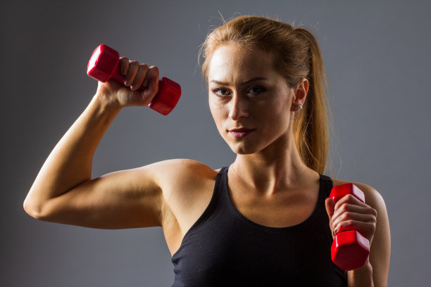 美丽的年轻白人健身妇女工作与手重量，手臂伸展建立力量。图片下载