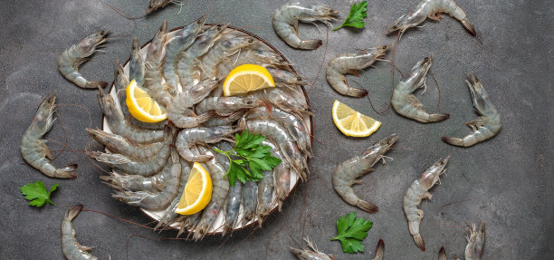 生虎虾配柠檬和香草，深色的背景。鲜虾。俯视图，平躺，横幅。图片下载