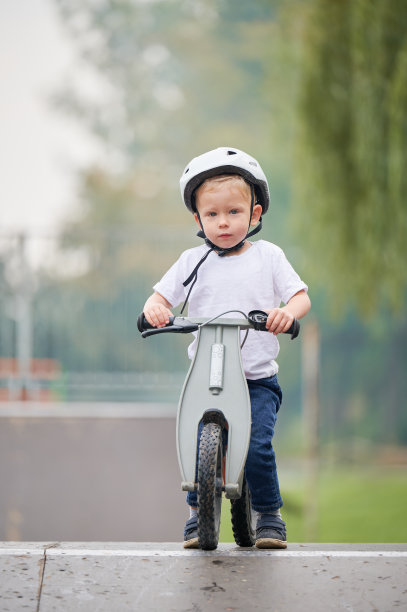 蹒跚学步的孩子在滑板公园学习骑跑步自行车。图片下载