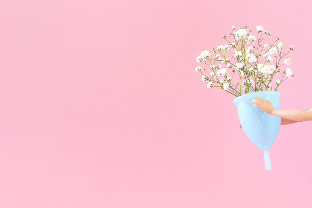 蓝色月经杯和花束精致的花朵在粉红色的背景与复制空间。女性亲密的卫生。女性健康理念，环保，零废物替代品图片下载