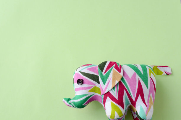 大象在一个绿色的背景，一个玩具大象在一个平原明亮的绿色薄荷背景图片下载