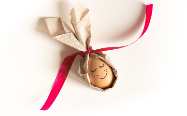 复活节彩蛋上画着嘴巴和睫毛，白色背景上有餐巾兔耳朵。2022年复活节乌克兰。复活节彩蛋，画着脸，系着红丝带图片下载