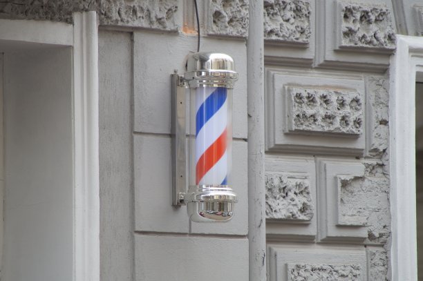 理发店的经典标志——理发店的杆子——以白、蓝、红三色螺旋的形式挂在理发店所在建筑的墙上图片下载