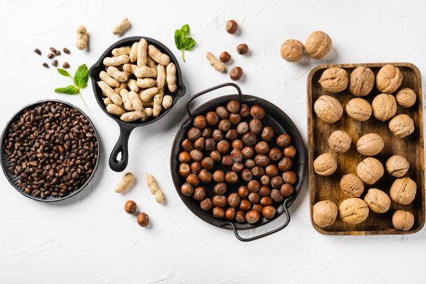 不同种类的坚果，花生，核桃，松子和榛子，在白石桌子的背景上，俯视图平躺图片下载