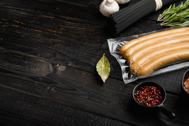 在真空包装的生鸡肉香肠，在黑色木制桌子背景上，与文本的复制空间图片下载