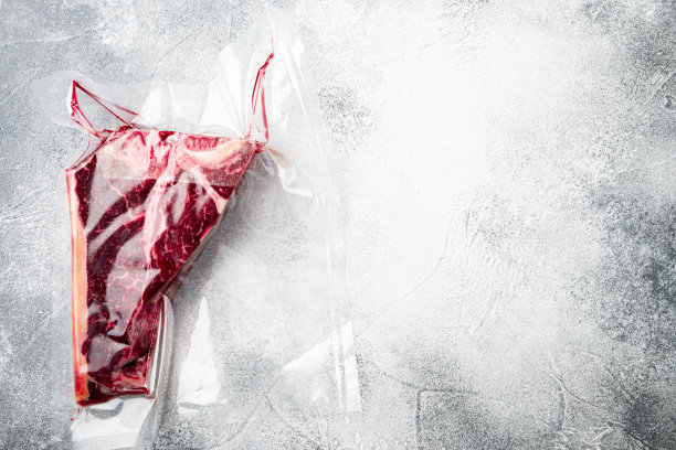 T骨或佛罗伦萨干熟牛排真空包装，在灰色石头背景，俯视图平躺，与文本复制空间图片下载