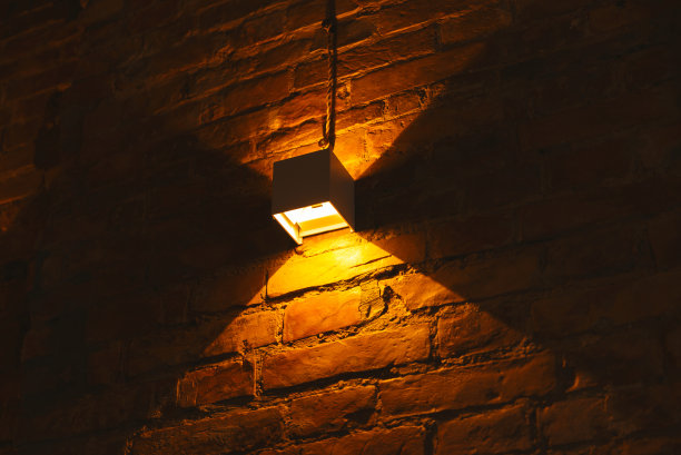 温暖的光关闭照片墙上的一盏灯与复制空间的砖。图片下载