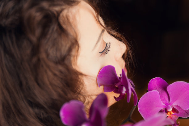 年轻和卷曲的女人的侧面肖像与粉红色的兰花图片下载