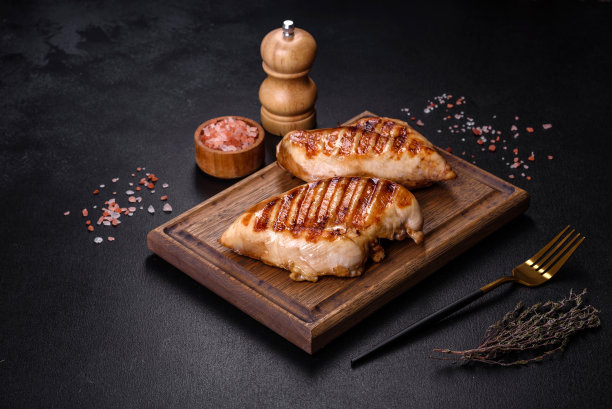美味新鲜的烤鸡胸肉，配香料和香草，深色水泥背景图片下载