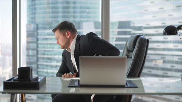 在一间豪华的办公室里，一位商人正坐在一张桌子旁。一位商人在摩天大楼的高层办公图片下载