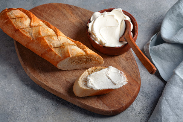 烤大蒜片面包法棍面包与村舍干酪服务砧板与蓝色亚麻餐巾灰色石头背景。面包店的概念。图片下载