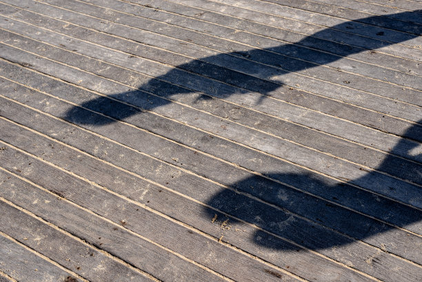 一个人的影子映在码头的木地板上。图片下载